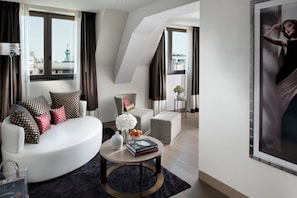 A modern living room with a white sofa, a round coffee table, and a city view through large windows.