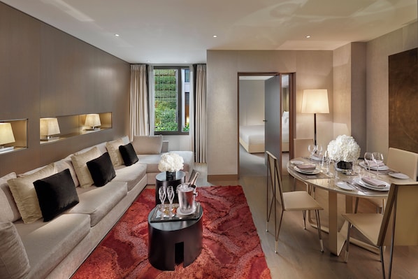 A modern hotel room with a sofa, dining table set for two, and a large window with curtains. - Mandarin Oriental, Paris (Paris)