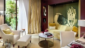 A modern living room with a sofa, armchairs, a coffee table, and a large artwork on the wall.