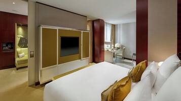 Una habitación de hotel con una cama grande, un escritorio con una silla, un televisor y un minibar.