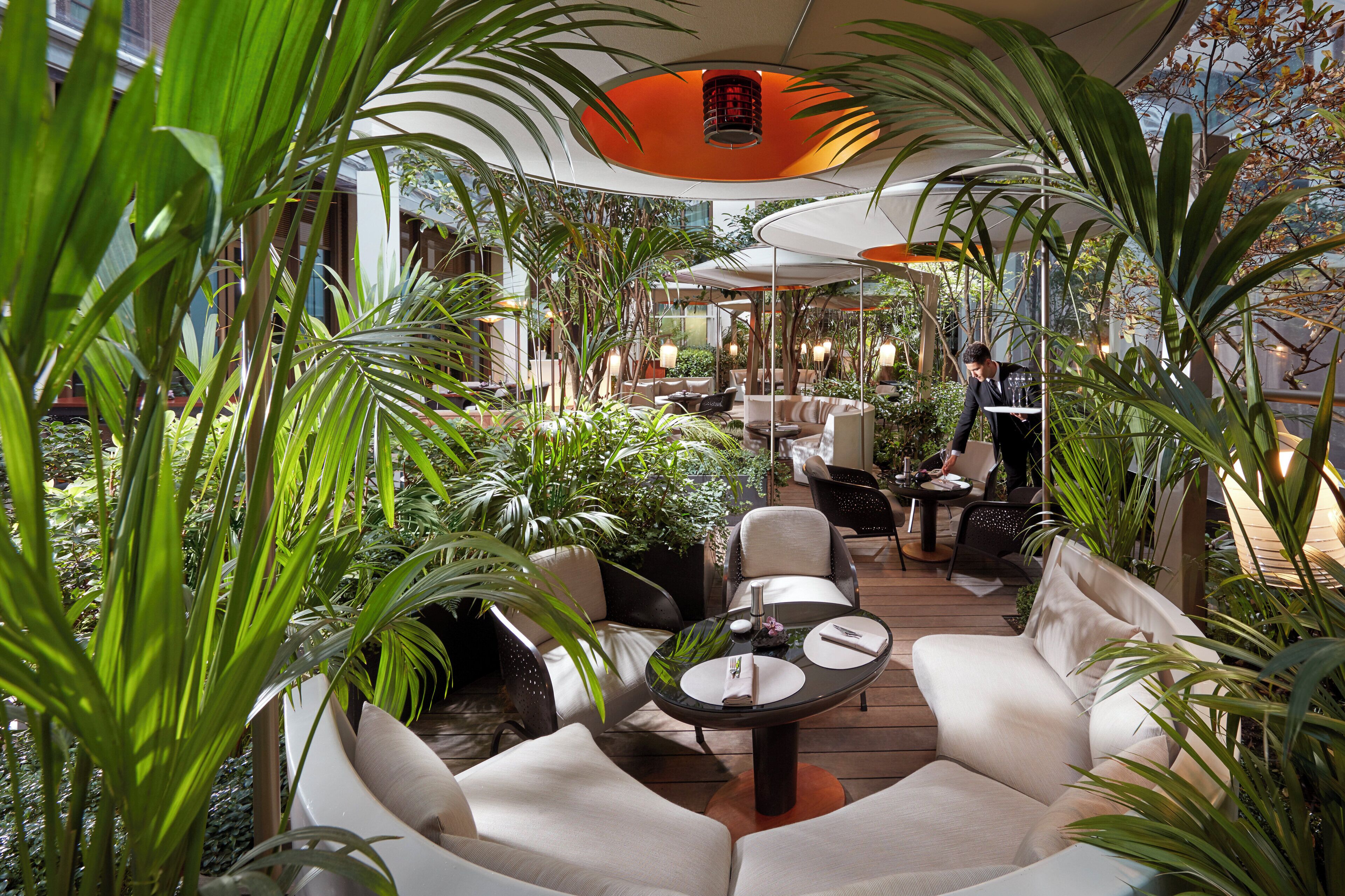 Un jardin intérieur aménagé avec des coins salon, des tables et un serveur.
