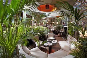 An indoor garden with seating areas, tables, and a waiter serving. - Mandarin Oriental, Paris (Paris)