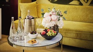 A table with a champagne bottle, glasses, a bowl of fruit, and a vase of flowers. - Mandarin Oriental, Paris (Paris)