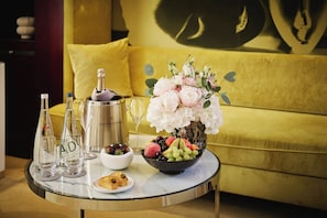 A table with a champagne bottle, glasses, a bowl of fruit, and a vase of flowers. - Mandarin Oriental, Paris (Paris)