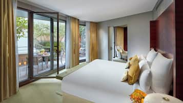 A modern hotel room with a large bed, a view of the outdoor patio, and a small table with candles.