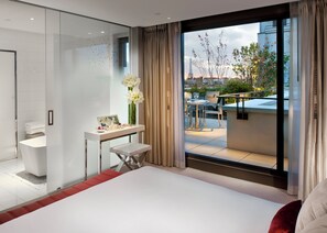 A modern hotel room with a large bed, a glass shower enclosure, a small vanity with toiletries, and a balcony with outdoor seating and a view of the Eiffel Tower. - Mandarin Oriental, Paris (Paris)