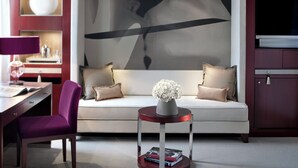 A modern living room with a sofa, a side table with a vase, a desk with a lamp, and a television.