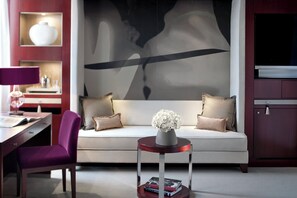 A modern living room with a sofa, a side table with a vase, a desk with a lamp, and a television. - Mandarin Oriental, Paris (Paris)
