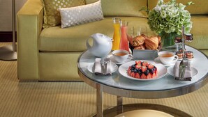 A room with a green sofa, a coffee table with breakfast items, and two framed pictures on the wall.