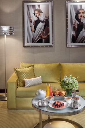 A room with a green sofa, a coffee table with breakfast items, and two framed pictures on the wall. - Mandarin Oriental, Paris (Paris)