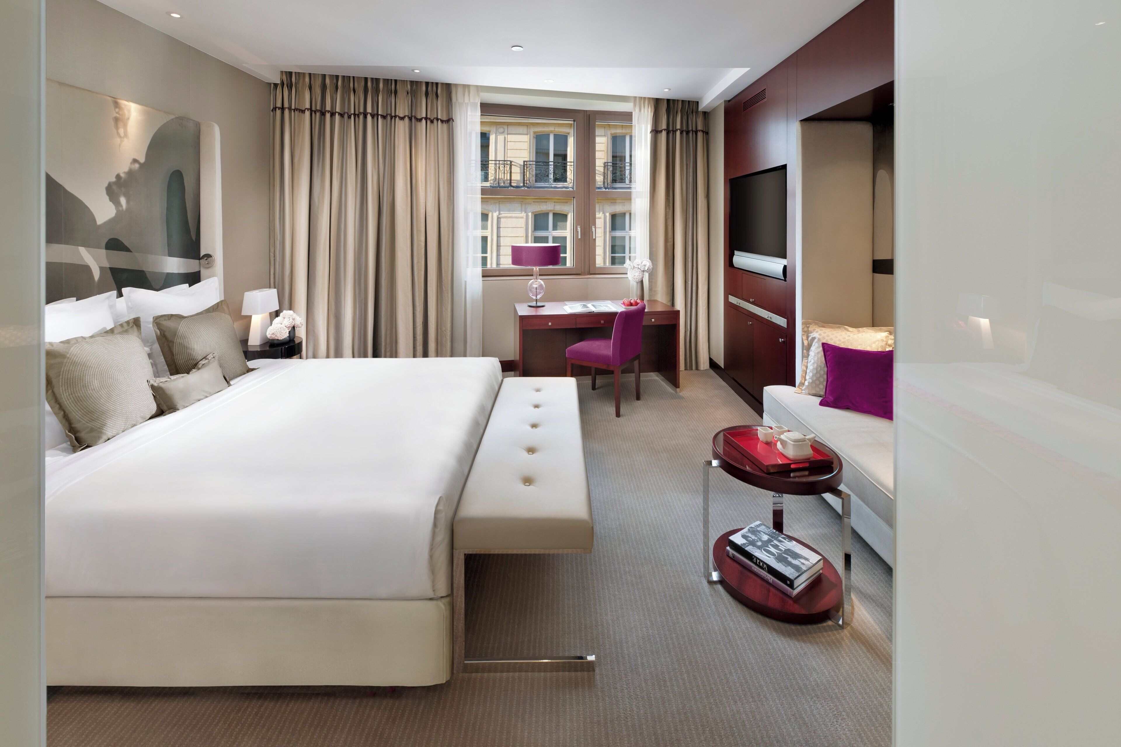 Een moderne hotelkamer met een groot bed, een bureau met een stoel, een televisie en een klein tafeltje met een boek.