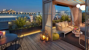 A rooftop terrace with a sofa, dining table, and chairs, overlooking a cityscape. - Mandarin Oriental, Paris (Paris)