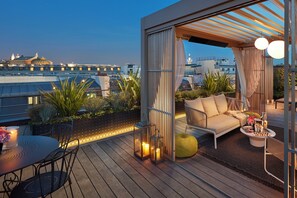 En takterrass med en sittgrupp, växter och utsikt över stadsbilden.