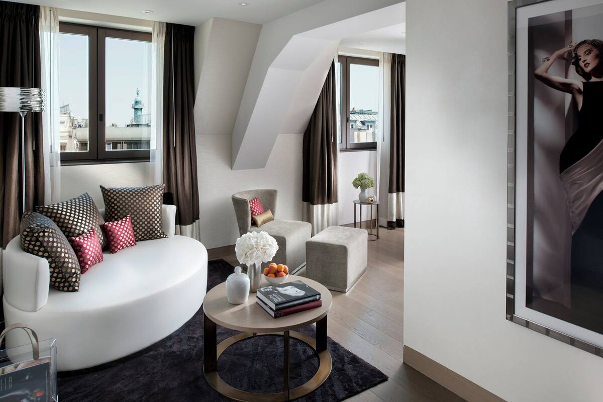A modern living room with a white sofa, a round coffee table, and a city view through large windows.