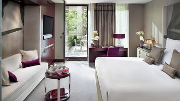 Une chambre d’hôtel avec un lit, un canapé, un bureau et un petit balcon agrémenté de plantes.