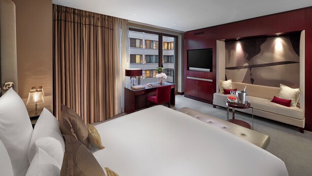 A modern hotel room with a large bed, a desk with a computer, a TV, and a seating area with a sofa and a small table. - Mandarin Oriental, Paris (Paris)
