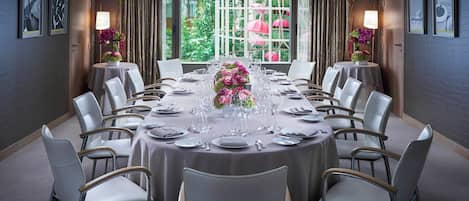 Un salón de conferencias con una mesa redonda, sillas y centros de mesa con flores.
