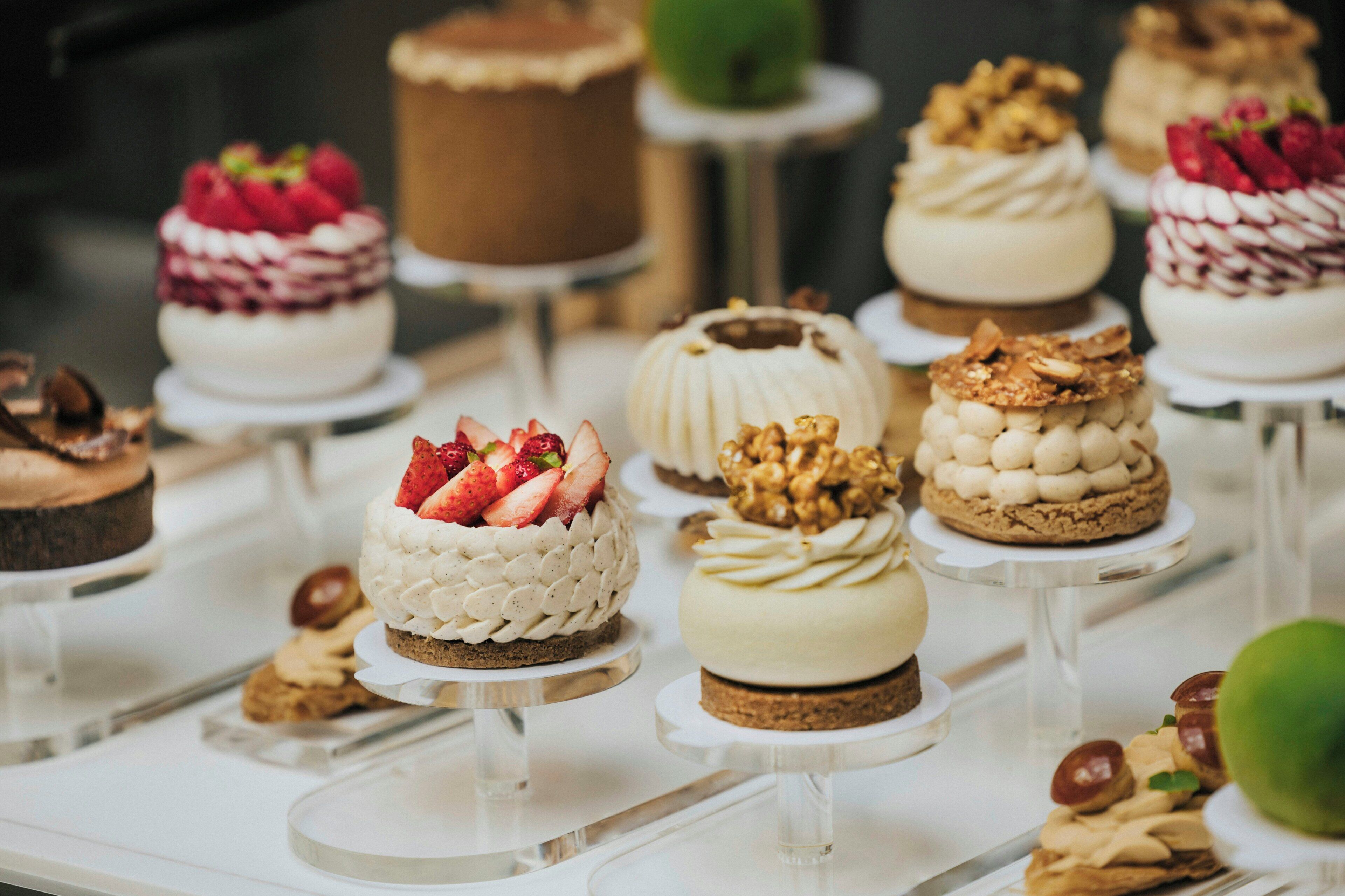 Variedad de postres a la vista, incluyendo pasteles con fresas y nueces, y un pastel de chocolate.