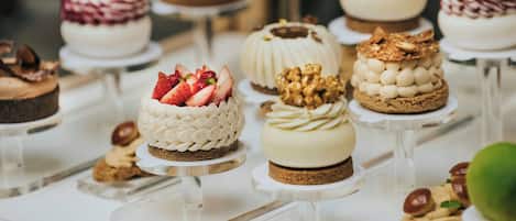 Variedad de postres a la vista, incluyendo pasteles con fresas y nueces, y un pastel de chocolate.