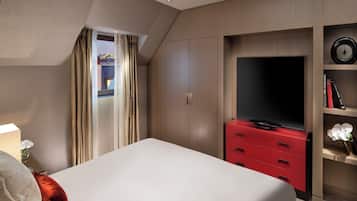 A hotel room with a bed, a TV, a red dresser, and a wardrobe.