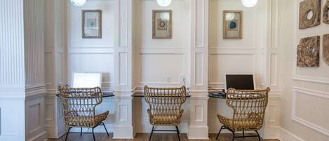 A room with three wicker chairs, a desk, and pendant lights.