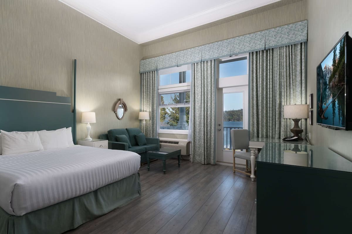Quarto de hotel com cama grande, escrivaninha, cadeira e televisão.