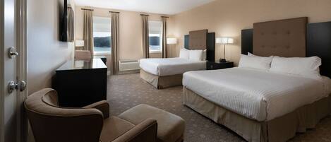A hotel room with two beds, a desk, a chair, and a TV.
