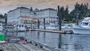 A marina with boats docked, a wooden dock, and a large building with multiple balconies in the background. - Prestige Oceanfront Resort, WorldHotels Luxury (Sooke)