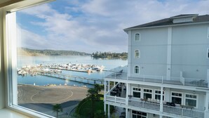 A view of a marina with boats docked, a dock extending into the water, and a building with a balcony overlooking the marina. - Prestige Oceanfront Resort, WorldHotels Luxury (Sooke)