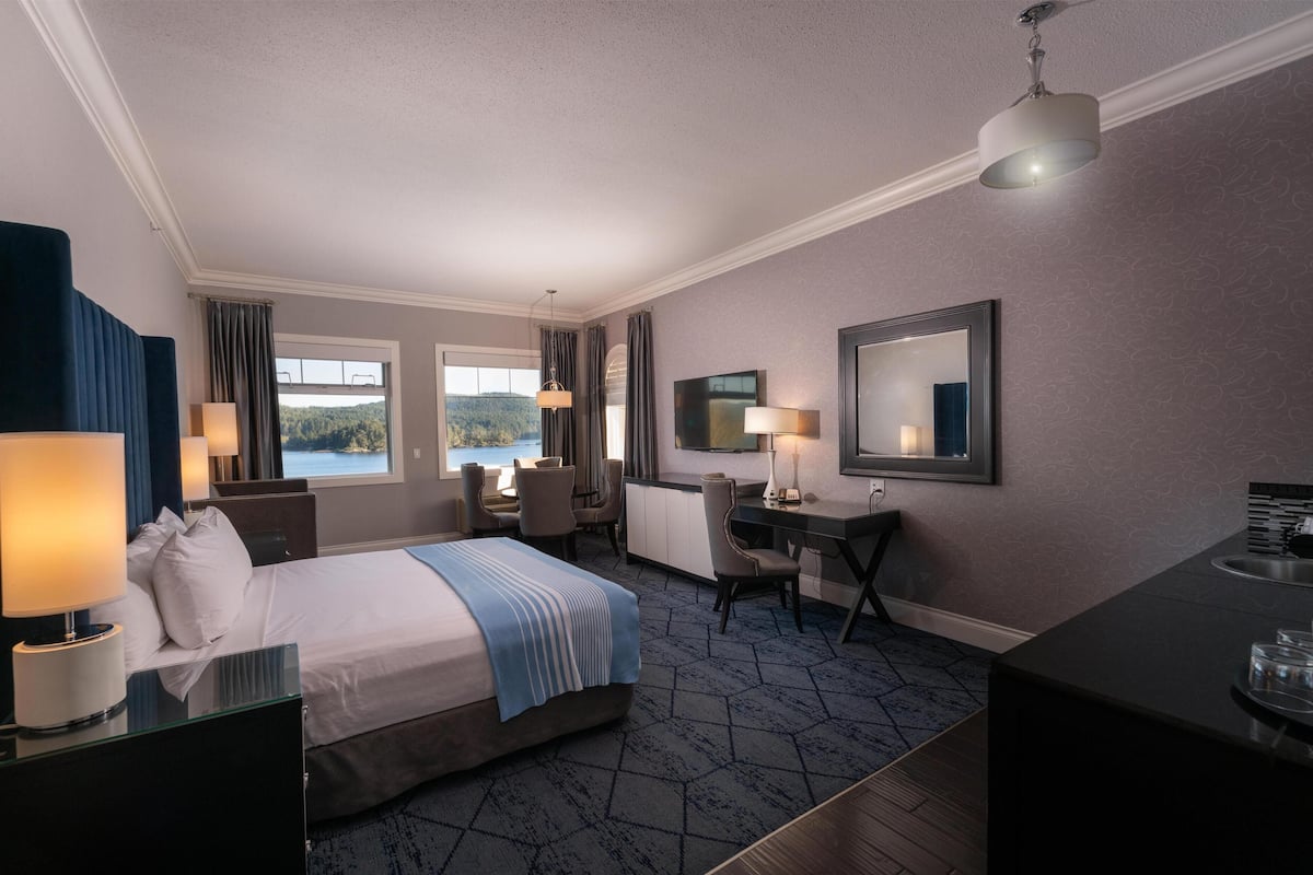 Quarto de hotel com cama, escrivaninha e televisão.