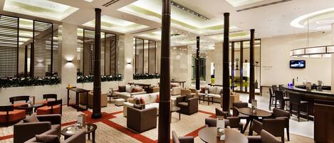 A spacious lobby with multiple seating areas, a bar, and a television screen.