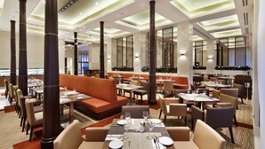 A modern restaurant with high ceilings, large pillars, and a mix of seating options including booths and tables. - Hilton Garden Inn Mardin (Mardin)