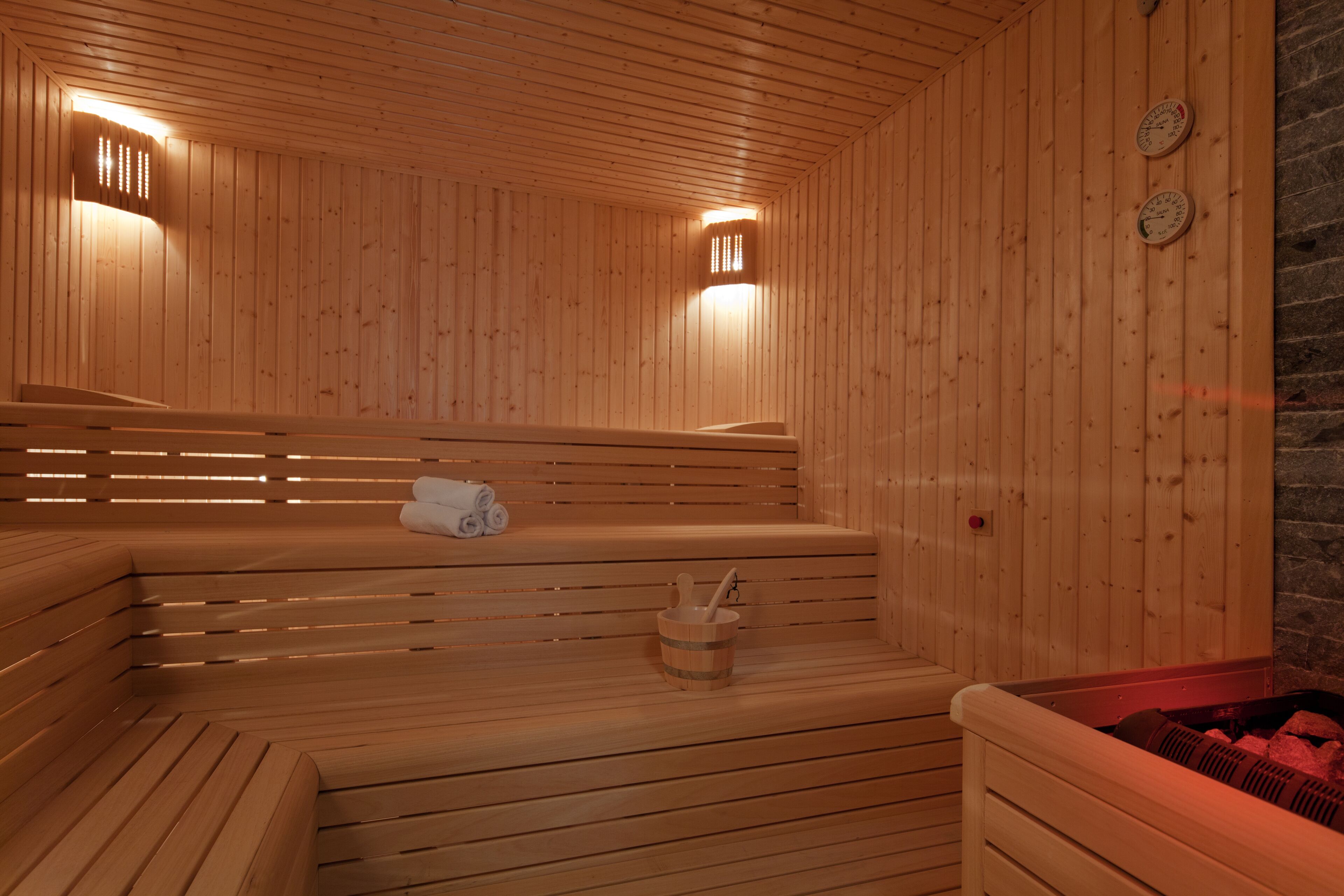 Un sauna en bois avec des bancs et un mur en pierre.