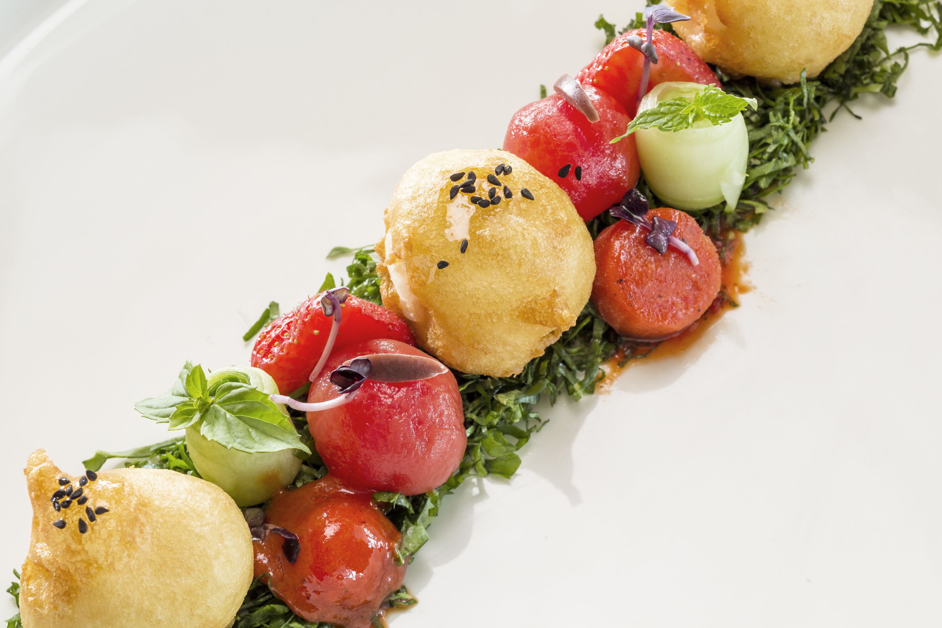 A dish with various vegetables and a breaded item on a white plate.