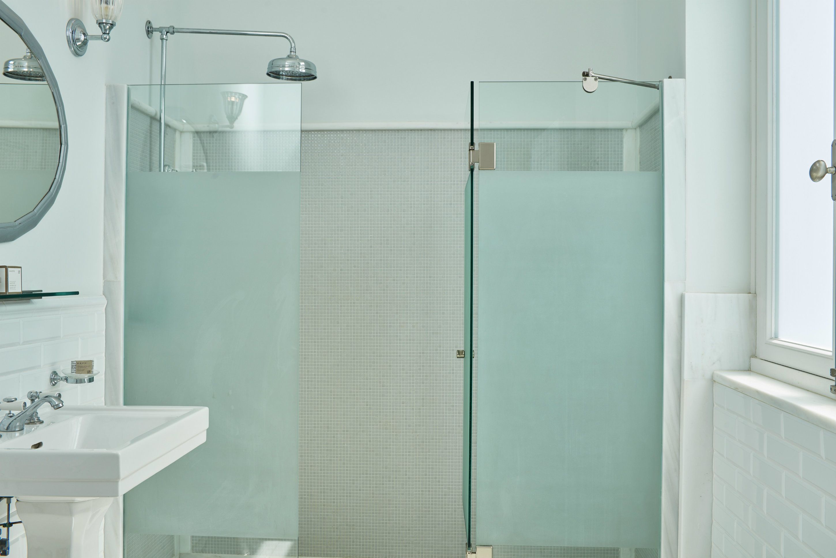 A modern bathroom with a glass-enclosed shower, a white sink, and a mirror.