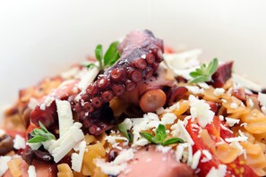 Ein Nahaufnahme eines Gerichts mit Oktopus, Tomaten und Käse.