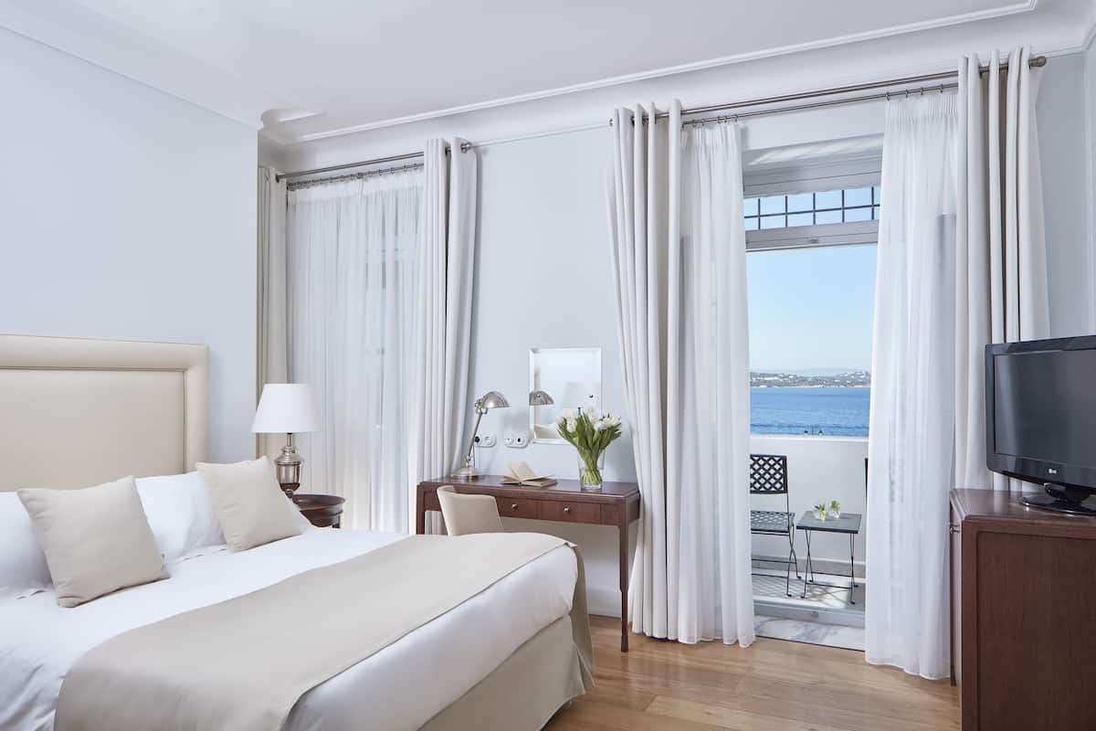 Ein Hotelzimmer mit Bett, Schreibtisch, Stuhl, Fernseher und Meerblick.