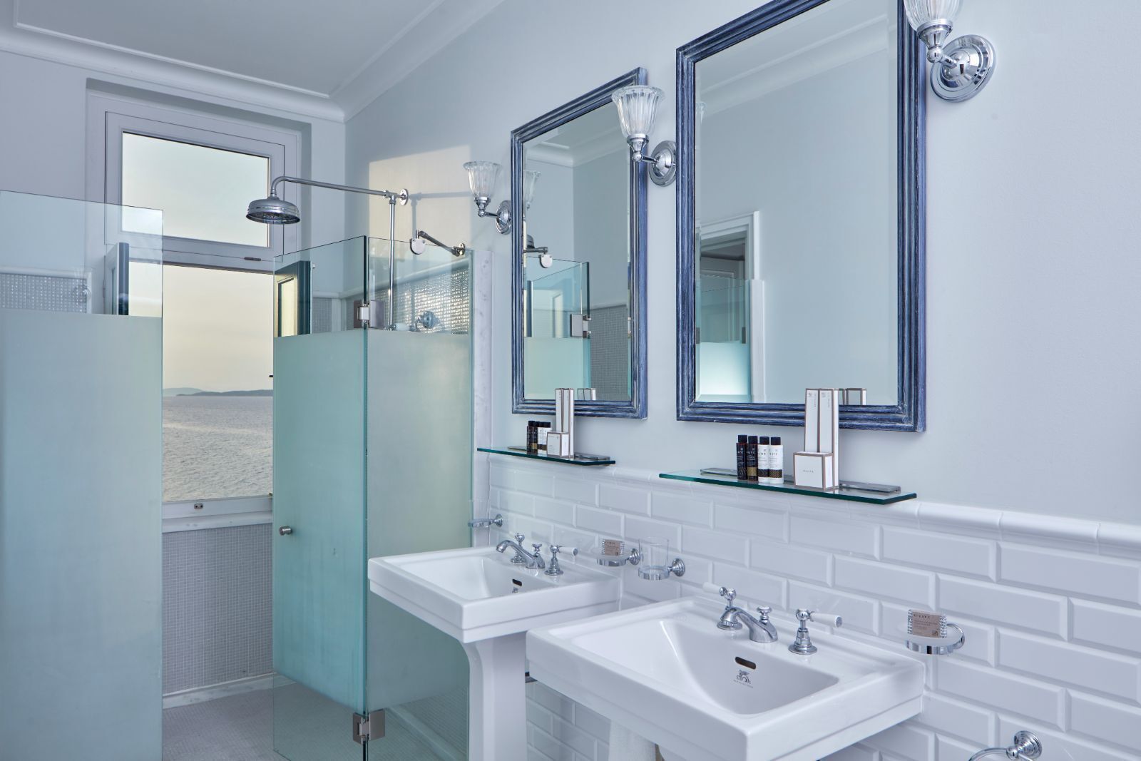 A modern bathroom with two sinks, a glass shower enclosure, and large mirrors.