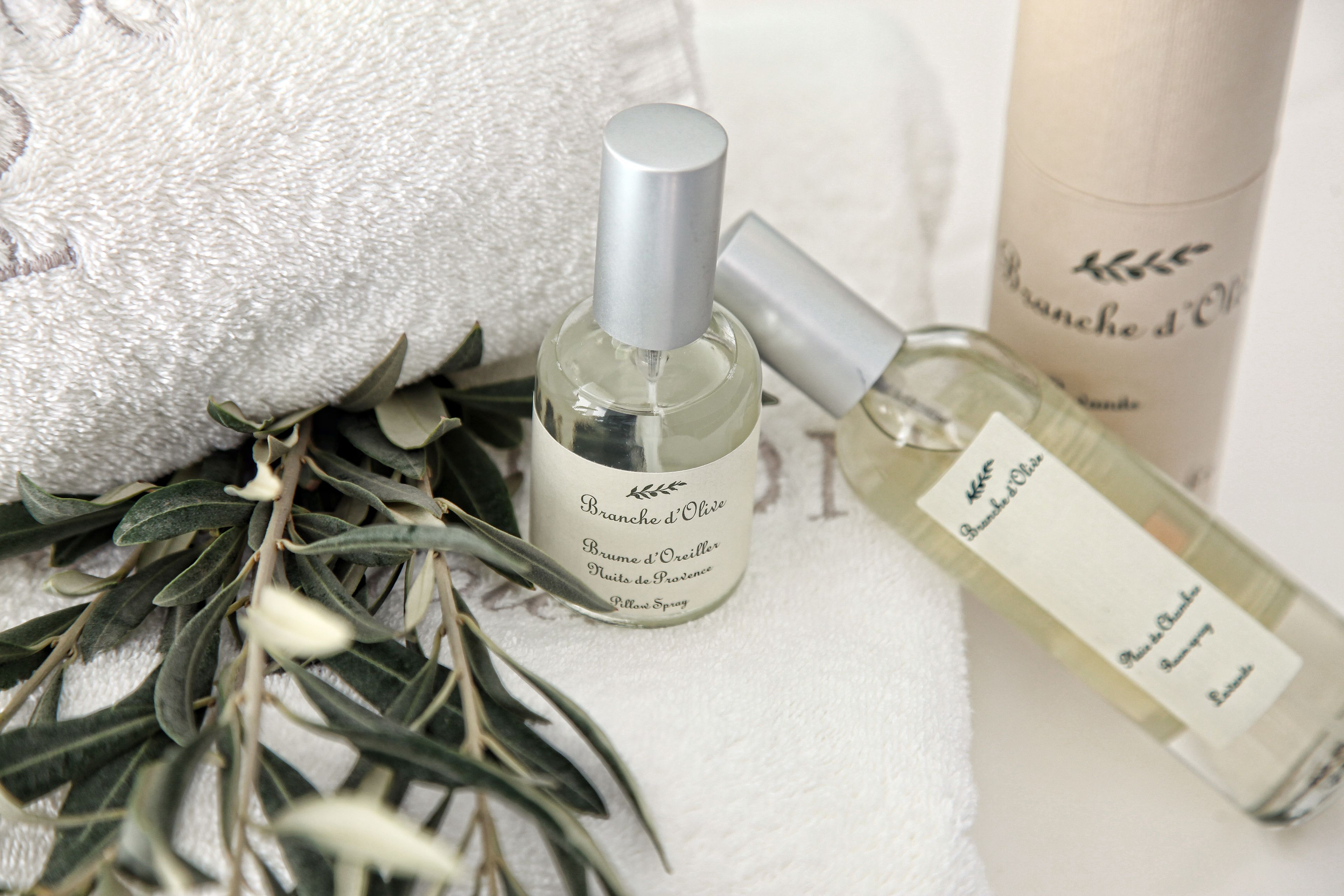 Two bottles of perfume and a white towel with green leaves.