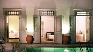 A hotel room with a view of a swimming pool, a bed, and a bathroom. - Poseidonion Grand Hotel (Spetses)