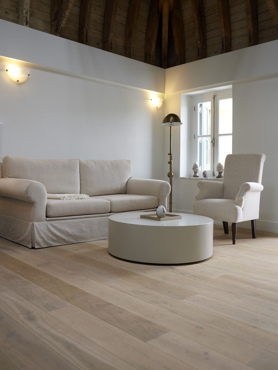 Una sala moderna con un sofá color crema, una mesita redonda y una lámpara de pie alta.