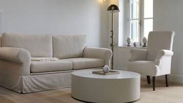Una sala moderna con un sofá color crema, una mesita redonda y una lámpara de pie alta.