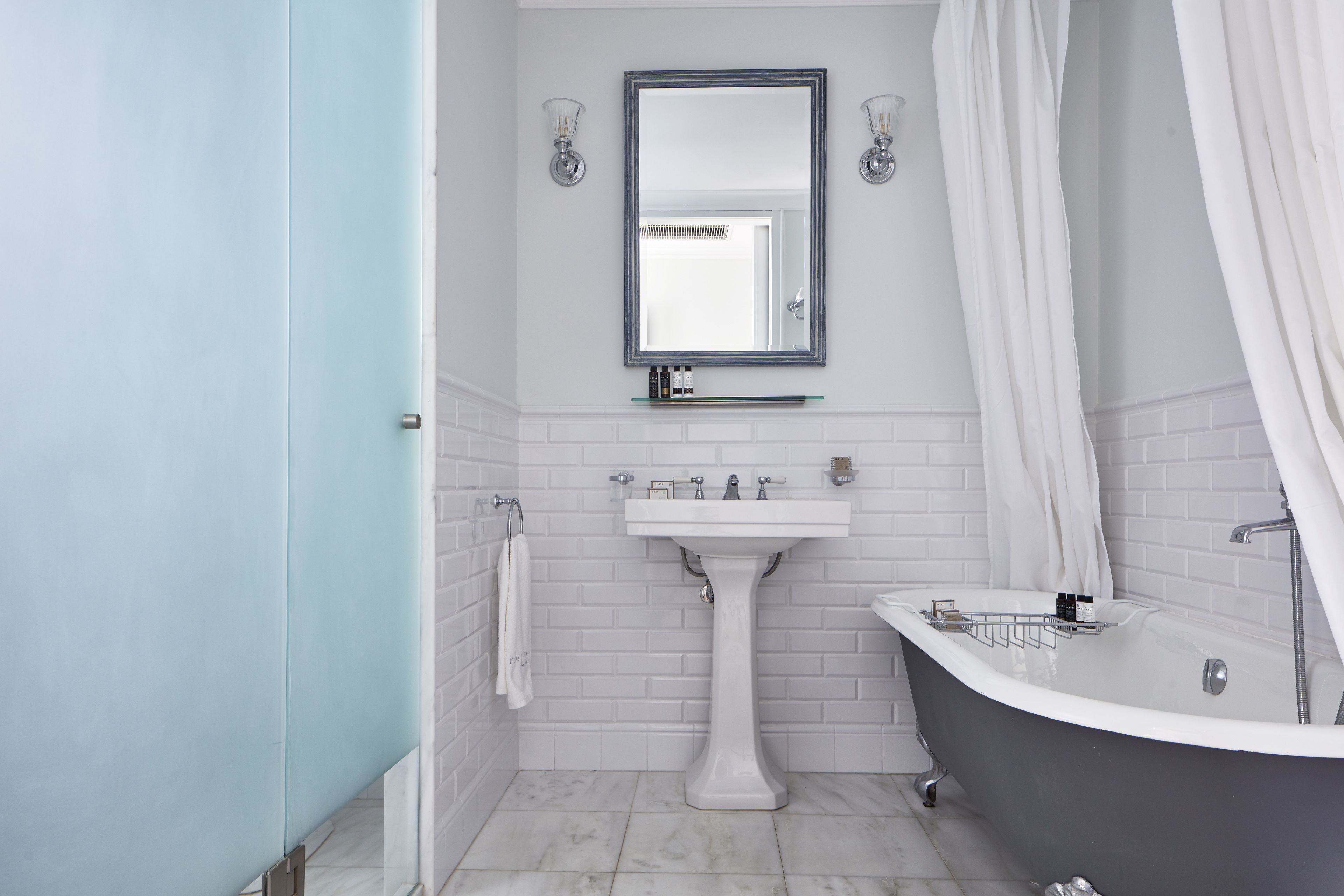 A bathroom with a freestanding bathtub, a pedestal sink, and a mirror above the sink.