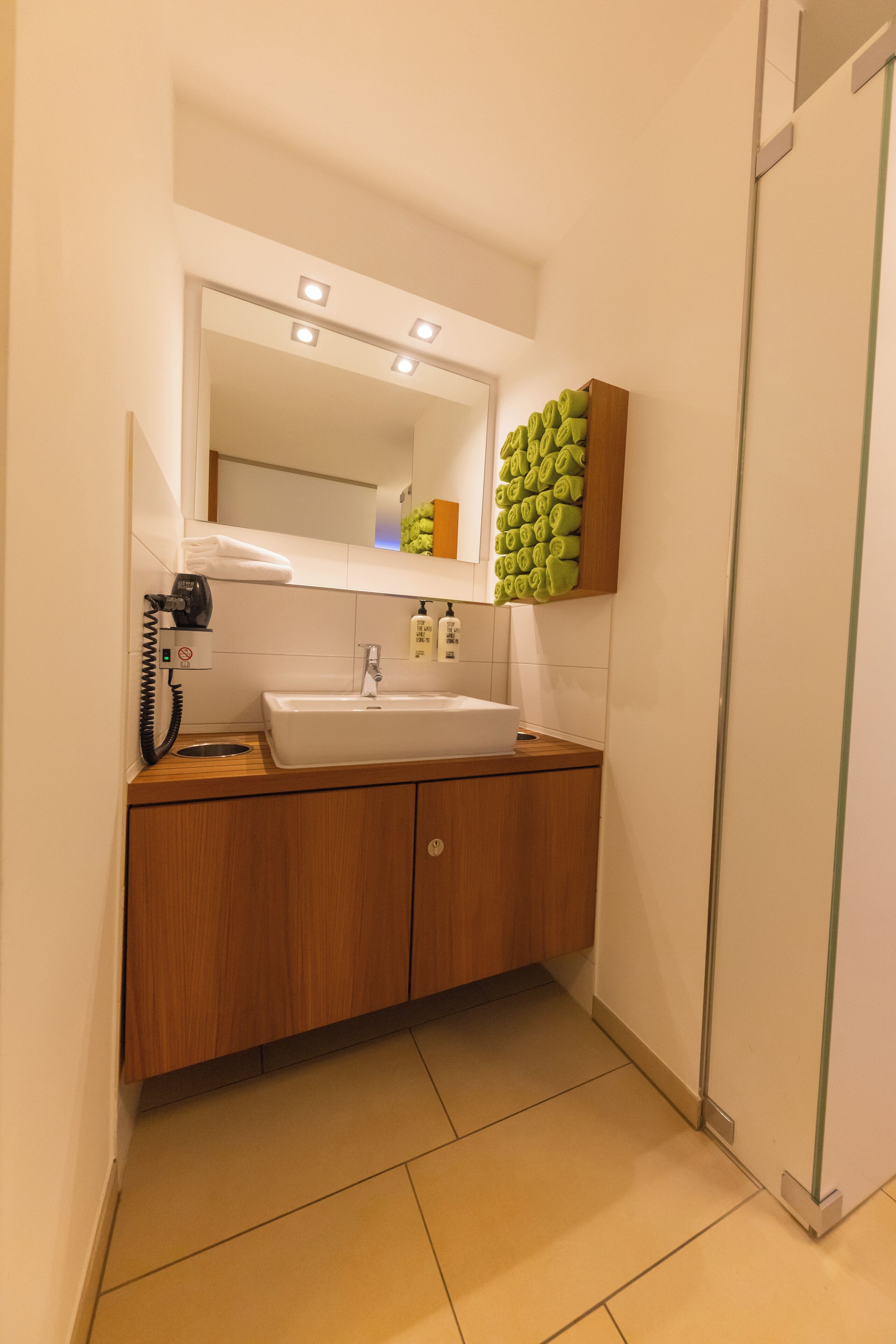 A modern bathroom with a white sink, wooden vanity, and a mirror above the sink.