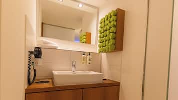 A modern bathroom with a white sink, wooden vanity, and a mirror above the sink.