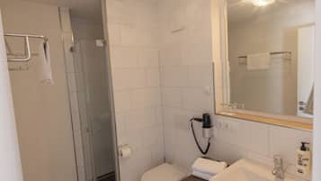 Ein modernes Badezimmer mit Duschkabine, Toilette, Waschbecken und Spiegel.