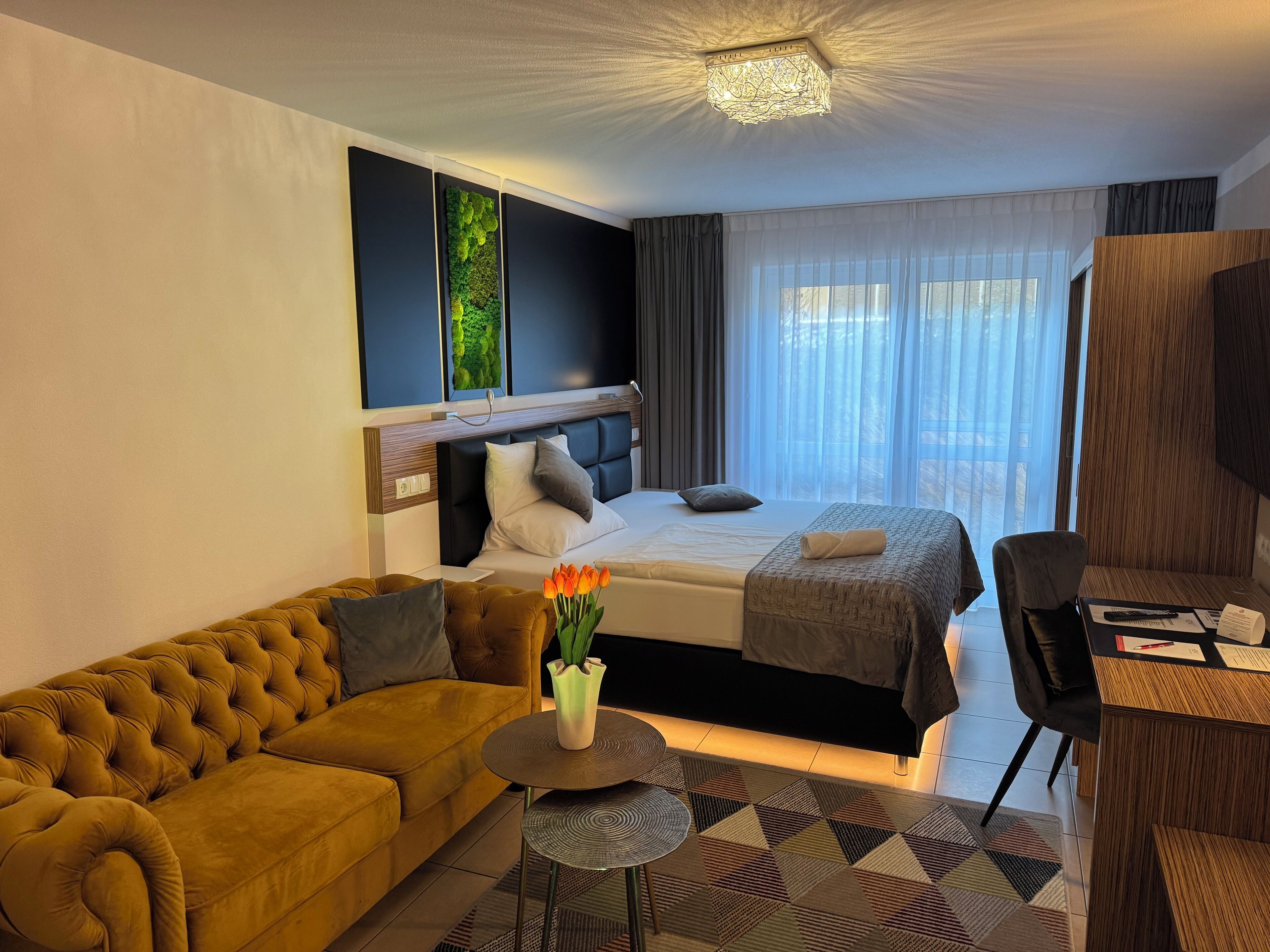A hotel room with a sofa, a bed, a desk, and a view of the outdoors.