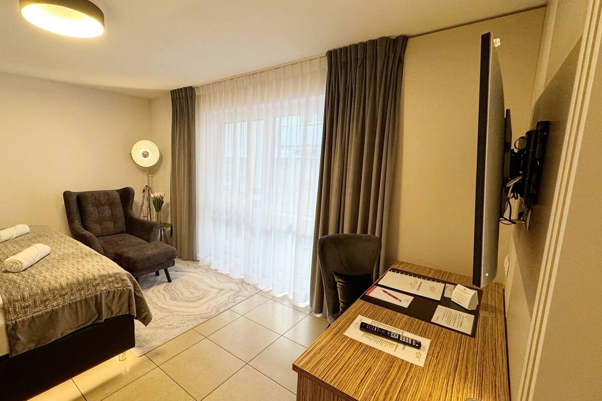 Ein Hotelzimmer mit zwei Betten, einem Schreibtisch, einem Stuhl, einer Lampe und einem Fernseher.