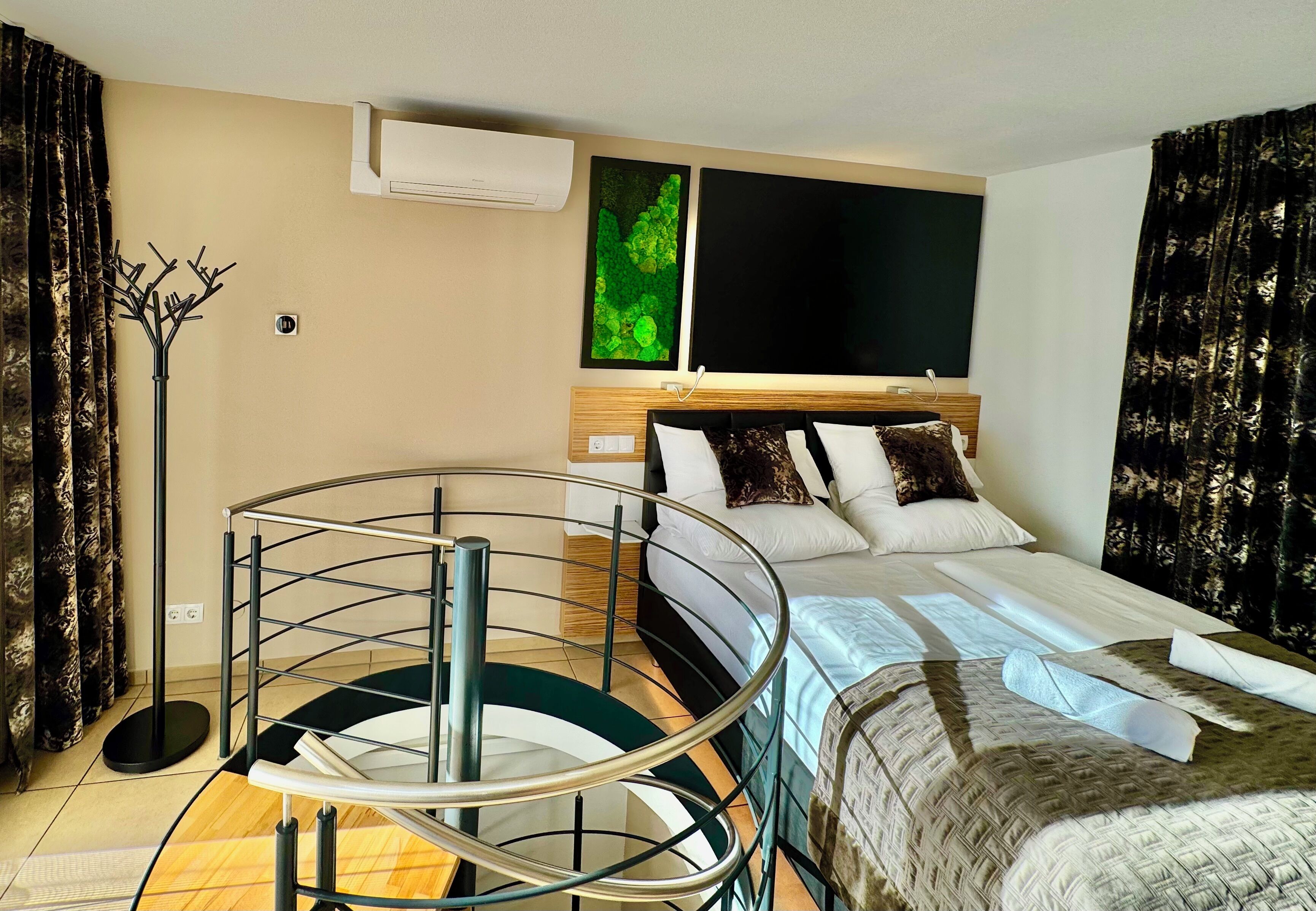 Habitación de hotel con cama, escalera de cristal redonda, televisor de pantalla plana y aire acondicionado de pared.