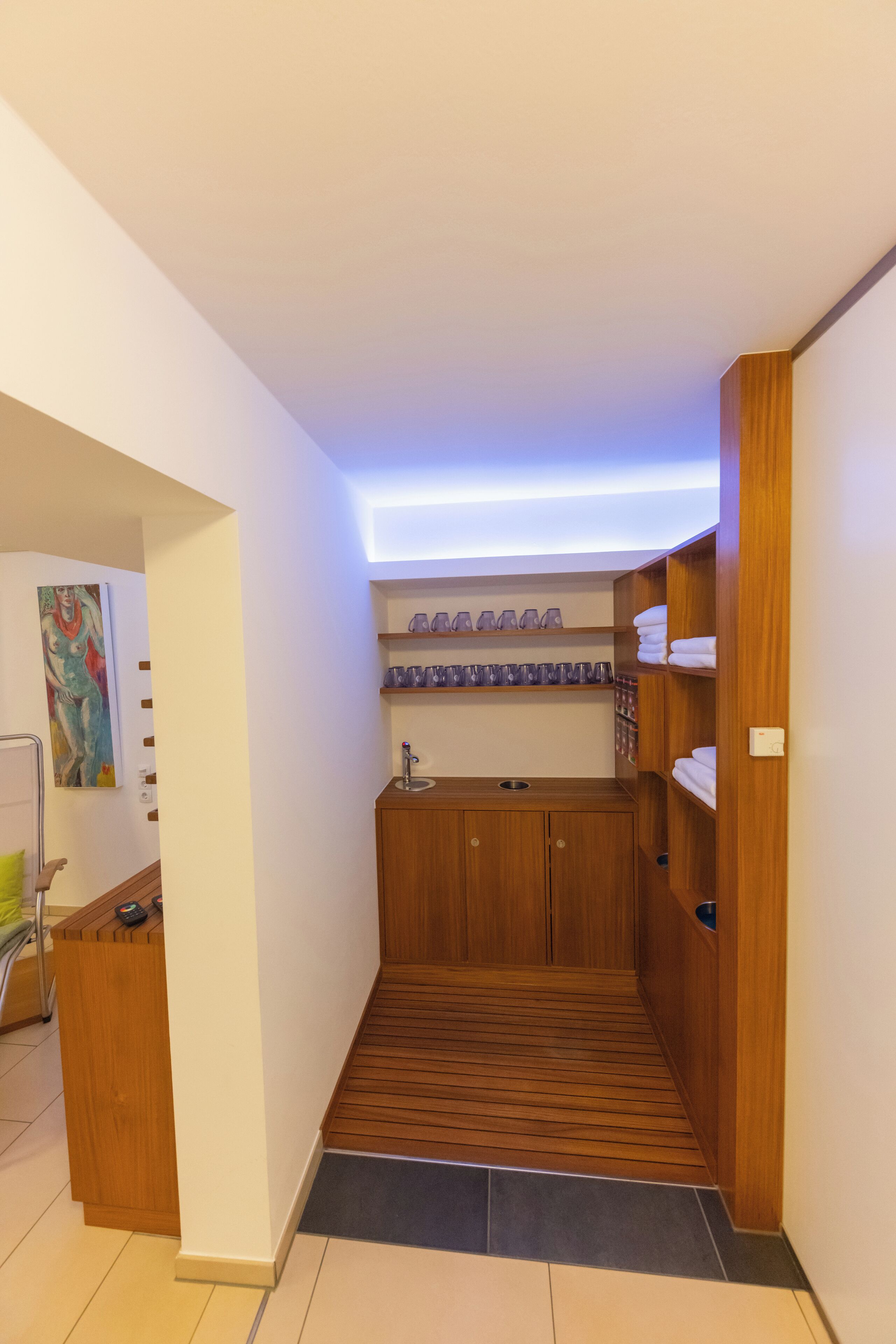 Ein kleines Badezimmer mit Holzschränken, einem integrierten Waschbecken und Ablageflächen für Pflegeprodukte.